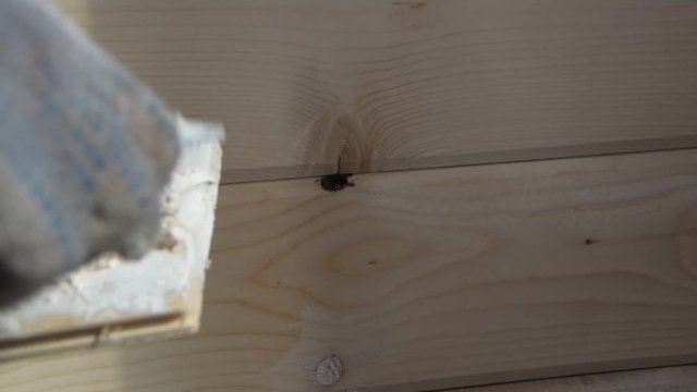 the worker puts putty on a hole in a wooden wall