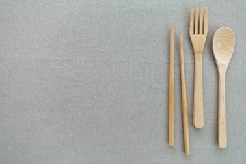 Reusable and environmentally friendly utensils, including bamboo spoon, fork and chopsticks on the side of beige or gray background. Copy space.