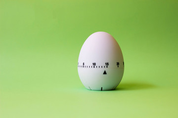 white egg timer on green background. Happy Easter in the kitchen. Home related, home staying. Free copy space.