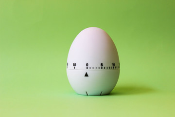 white egg timer on green background. Happy Easter in the kitchen. Home related, home staying. Free copy space.