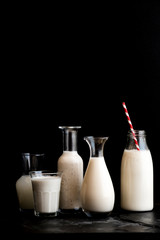 Milk in Bottles with Red Paper Straw on black surface