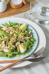 Arugula and trout salad with egg and asparagus on a plate on a table covered with a tablecloth and appliances vertical arrangement