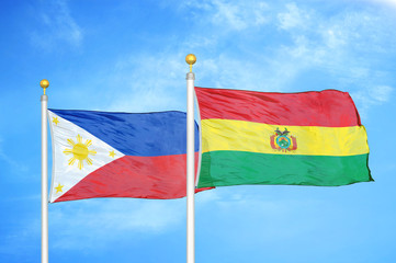Philippines and Bolivia two flags on flagpoles and blue cloudy sky