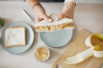 women's hands hold a peanut butter and banana sandwich