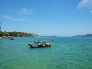 Naklejka na ściany i meble Longtail boats anchored near coast of tropical island. Traditional longtailboat in Thailand. Old fishing asian wooden boat. Panorama of beautiful sea and green islands. Azure clean transparent water 