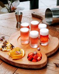 glasses of beer with froth and sliced fruits on the board