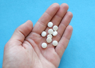 Male hand holds white medicinal pills in the palm of your hand.