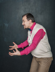 Funny teacher or business man holding something in his hands on blackboard