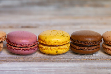 Assortment of delicious traditional french macaroons. Colorful sweet dessert for real gourmands. Lemon, chocolate, caramel, raspberry flavors. Wooden rustic background, copy space, close up, macro