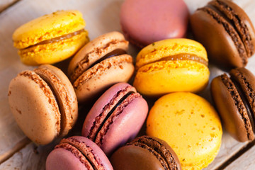 Fototapeta na wymiar Assortment of delicious traditional french macaroons. Colorful sweet dessert. Lemon, chocolate, caramel, raspberry flavors. Wooden background, craft paper, close up, macro, flat lay top view