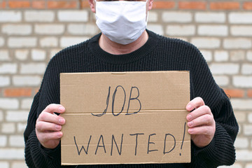 concept unemployment and coronavirus a man in a medical hygienic mask is holding a cardboard tablet...