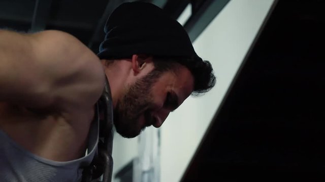 Young beard male athlete in sportswear doing dips on parallel bars in the gym. Close up shot of athlete.