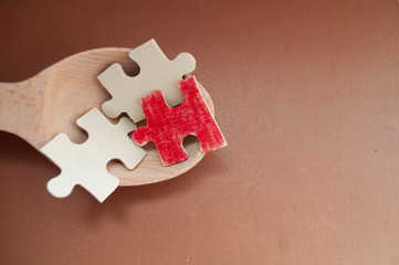 red puzzle piece among simple puzzle pieces on a wooden spoon, leadership, marketing concept, social media influence, HR recruiter, concept stand out