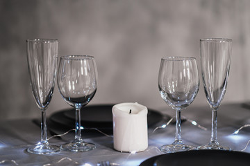 A table set in the restaurant. Serving a table. Grey artistic background. Black matte utensils, glass glasses. White candles and decor.