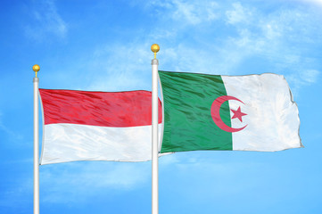 Indonesia and Algeria two flags on flagpoles and blue cloudy sky