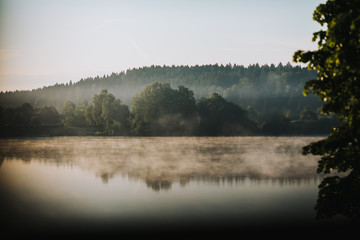 autumn fog over the reflecting forest lake