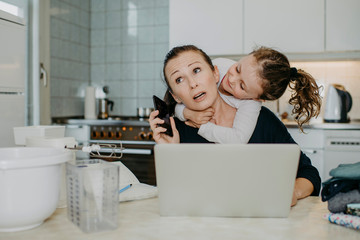 Mutter mit Tochter beim Home Office in der Küche