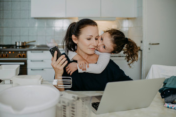 Mutter mit Tochter beim Home Office in der Küche