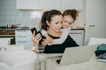Mutter mit Tochter beim Home Office in der Küche