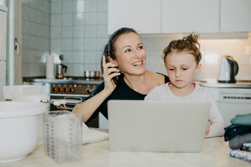 Muter mit Tochter beim Home Office in der Küche