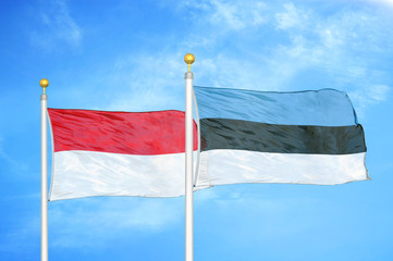 Indonesia and Estonia two flags on flagpoles and blue cloudy sky