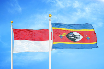 Indonesia and Eswatini Swaziland two flags on flagpoles and blue cloudy sky