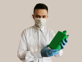 A medical worker in gloves and a mask holds in his hands a bottle with an antiseptic