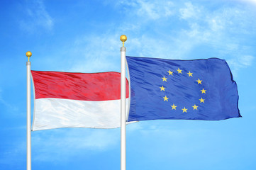 Indonesia and European Union two flags on flagpoles and blue cloudy sky