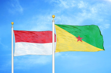 Indonesia and French Guiana two flags on flagpoles and blue cloudy sky