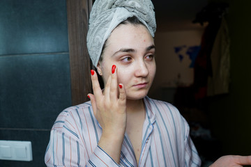 Woman uses face care cream. Facial skin care at home. Beauty treatments at home.