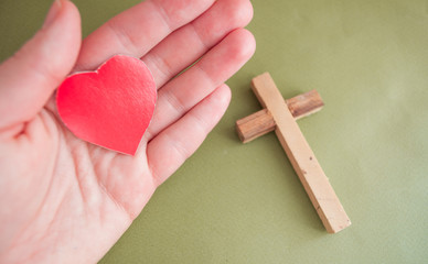 hand holds a red heart and next to a wooden cross, a prayer for loved ones, healthcare, love, organ...