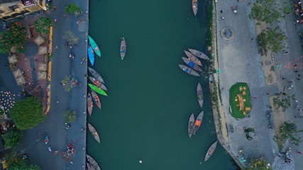 Aerial top down view of colourful long tail boats moored to embankment on Thu Bon river, Hoi An ancient town, Quang Nam province, Vietnam. Popular travel destination.