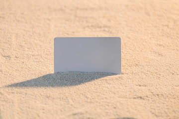 Empty white card put on the sand beach