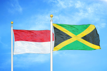 Indonesia and Jamaica two flags on flagpoles and blue cloudy sky