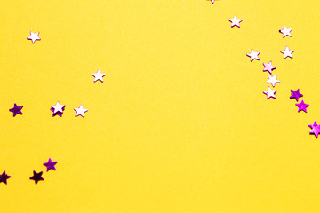 Fototapeta Closeup asterisks sprinkled on a yellow isolated background. View from above. obraz