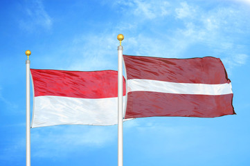 Indonesia and Latvia two flags on flagpoles and blue cloudy sky