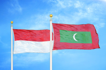 Indonesia and Maldives two flags on flagpoles and blue cloudy sky