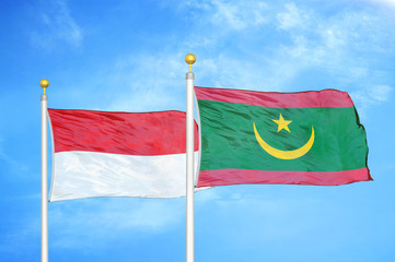 Indonesia and Mauritania two flags on flagpoles and blue cloudy sky