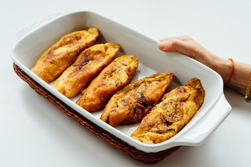 Female hand holding a tray with torrijas, a typical Spanish sweet fried toasts of sliced bread soaked in eggs and milk, on white background