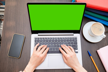 Business, internet shopping, technology and people concept - close up of woman with online shop web page on laptop screen and coffee on wooden table. Stay at home woman working remotely on laptop. 