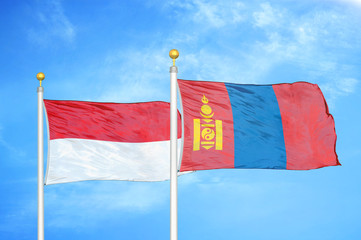 Indonesia and Mongolia two flags on flagpoles and blue cloudy sky