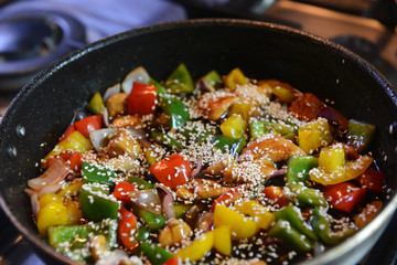 Freshly prepared stir fry with chicken and vegetables including onions, red, yellow and green capsicum in a wok