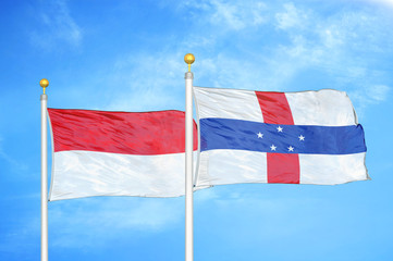 Indonesia and Netherlands Antilles two flags on flagpoles and blue cloudy sky