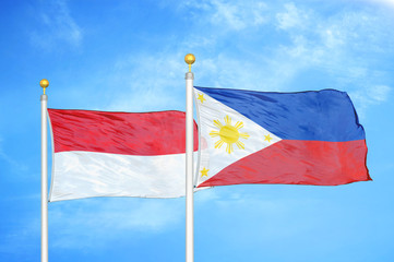 Indonesia and Philippines two flags on flagpoles and blue cloudy sky