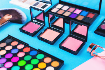 Makeup and beauty products on pink and blue background. Eye shadow palettes. fan contouring brush...