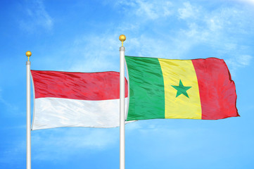 Indonesia and Senegal two flags on flagpoles and blue cloudy sky