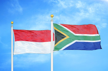 Indonesia and South Africa two flags on flagpoles and blue cloudy sky