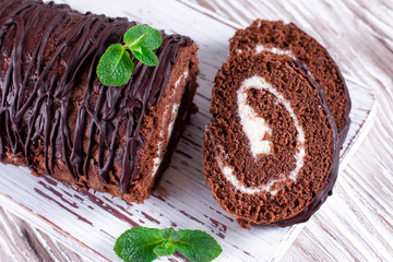 Delicious chocolate roll sponge cake with vanilla cream and mint leaves.