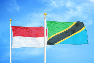 Indonesia and Tanzania two flags on flagpoles and blue cloudy sky