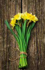 bouquet of fresh spring flowers daffodils on a wooden background. Top view